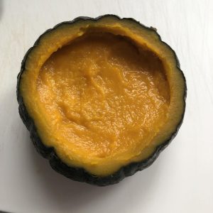 Spoon the seasoned pumpkin puree back into the hollowed-out pumpkin shell and spread it evenly.