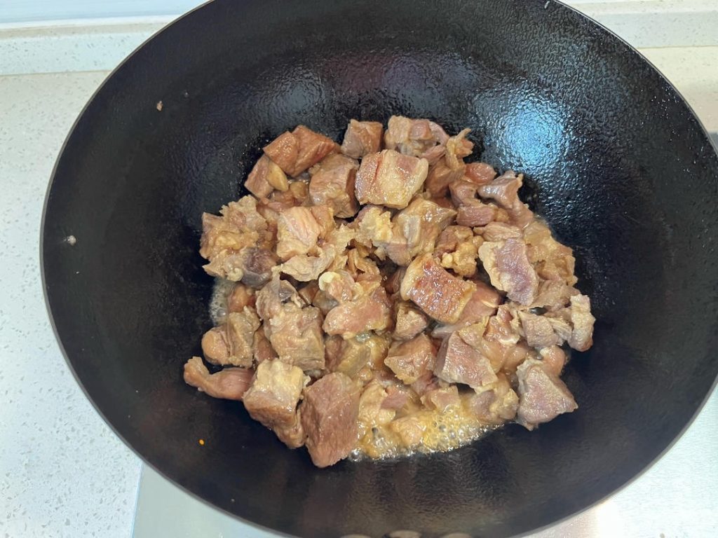 As soon as the sugar turns yellow, immediately add the drained beef chunks.