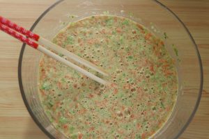 Add the finely chopped broccoli and carrot to the egg batter.