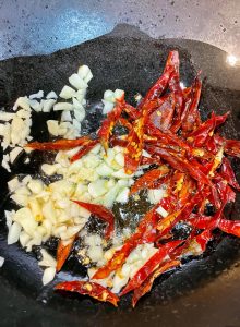 Add the garlic, dried chilies, and Sichuan peppercorns.
