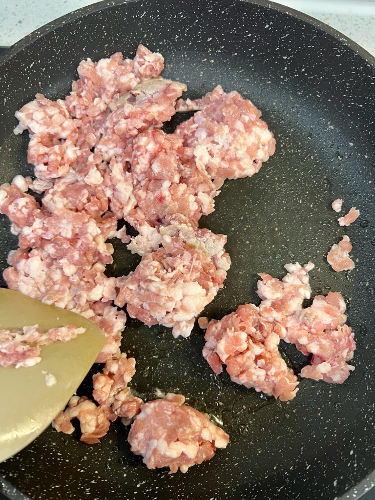 Add the minced pork and stir-fry, breaking it up, until it's cooked through and no longer pink.