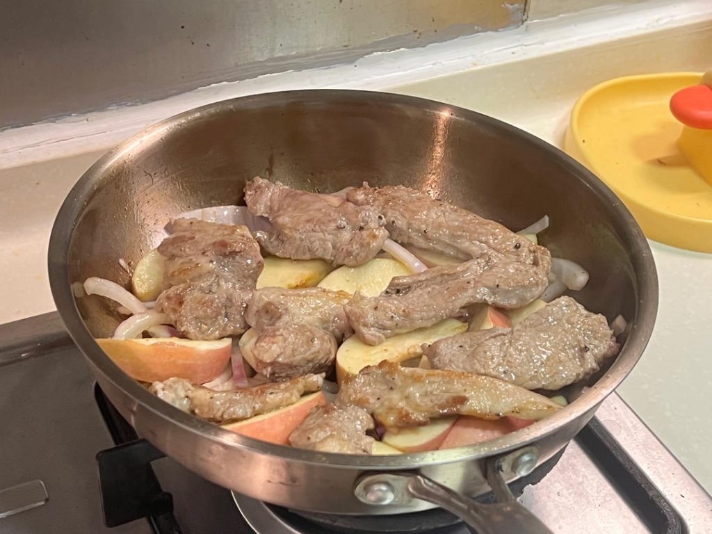 Lay the seared pork steaks on top of the bed of onions and apples
