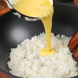 The Egg Pour: Pour the beaten egg liquid directly over the hot rice.
