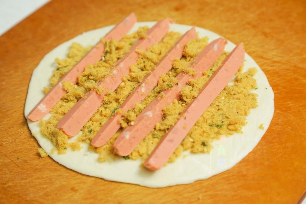 Place a pancake on your work surface. Spread a generous layer of pork floss over the surface. Arrange about 5 strips of the ham sausage on top of the pork floss.