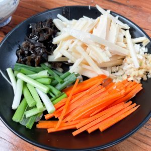 Slice the Veggies: Julienne the carrot and bamboo shoots.