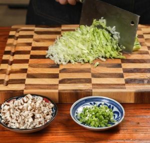 Dice the shiitake mushrooms into small cubes. Slice the iceberg lettuce into thin shreds. Chop the scallions into rings. Crack the two eggs into a bowl and beat them well until the yolk and white are fully combined.