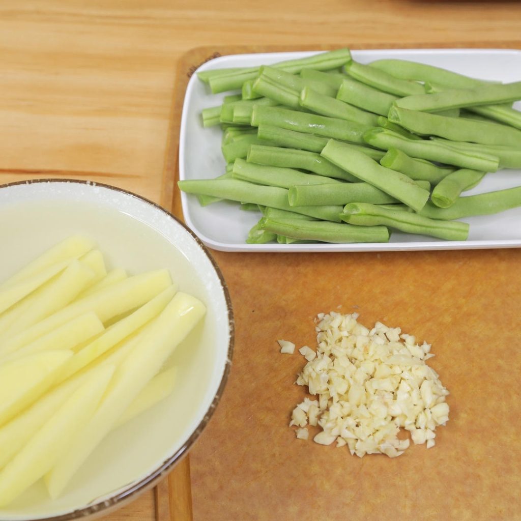 Wash the green beans, trim the ends, and break or cut them into finger-length segments (about 3 inches). Peel the potato and cut it into thick strips/batons, roughly the same size as the green beans. Finely mince the 5 cloves of garlic.