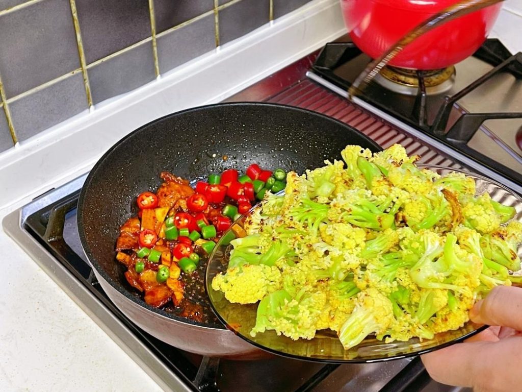 Add the sliced peppers and the pre-cooked cauliflower back into the wok.