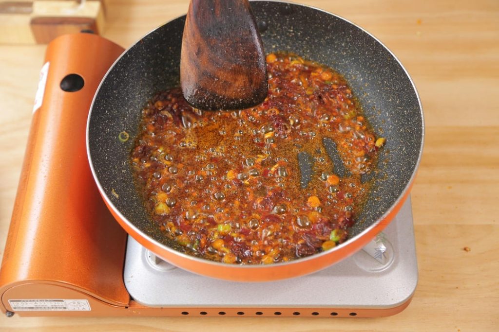Add 1 tablespoon of Doubanjiang to the aromatics. Turn the heat to low and stir-fry the paste gently. You want to see the oil turn a beautiful red color. This releases the aroma of the fermented beans.