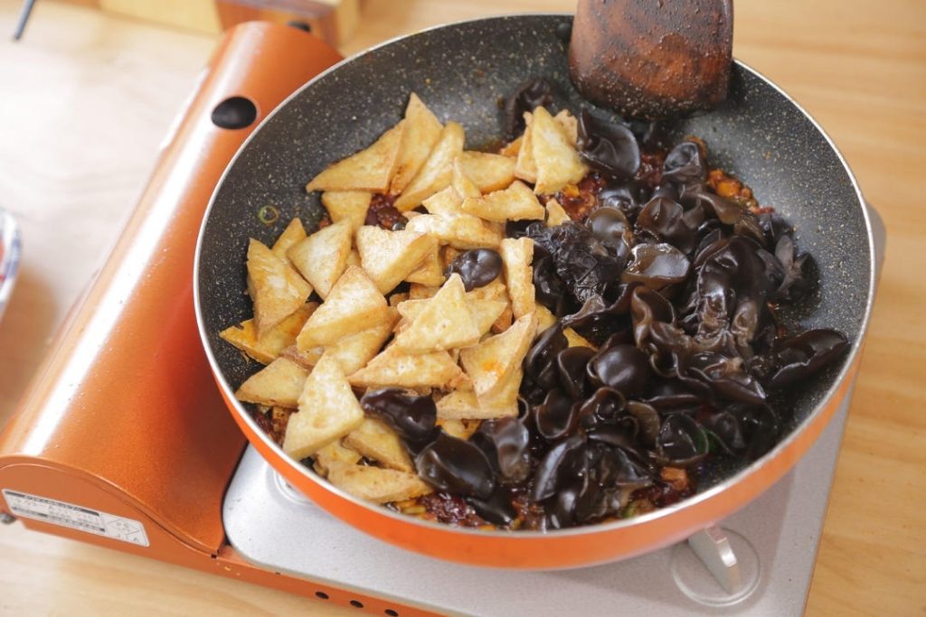 Add the blanched wood ears and the fried tofu back into the wok. Stir gently to coat them in the red oil.