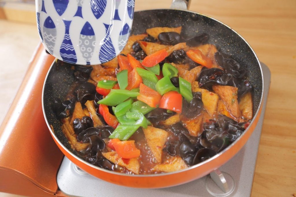 Add the blanched peppers to the wok. Let everything simmer for a minute so the flavors meld.