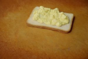 Layer 1: Take the first slice of toast. Spread the egg salad mixture generously over one side.