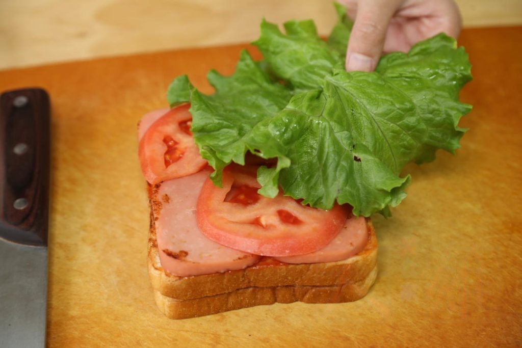 Fill: Layer the seared ham, tomato slices, and lettuce on top of the ketchup.