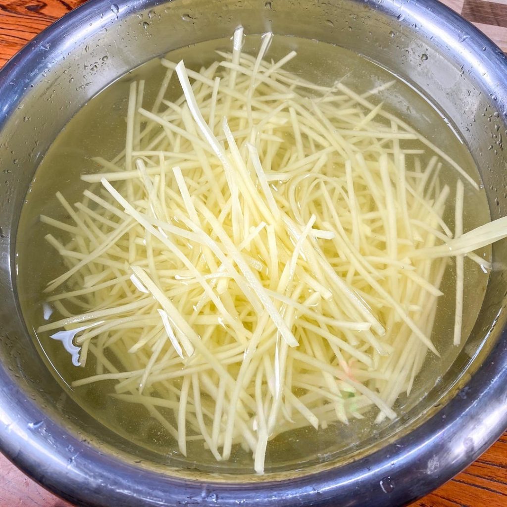 The Crucial Wash: Place the potato shreds in a large bowl of water