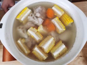 After the pork has simmered, add the drained lotus root, corn, and carrots. Continue to simmer for another 15 minutes.