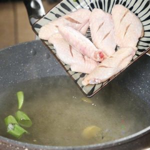 Turn the heat down to low/medium-low. Carefully place the chicken wings into the water.