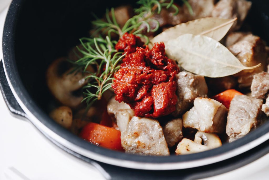Season Add the tomato paste, bay leaves, and rosemary sprig.