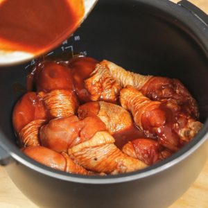 Place the marinated drumsticks on top of the aromatics. Pour any remaining marinade from the bowl over the chicken. Add an additional 5 spoons of water.