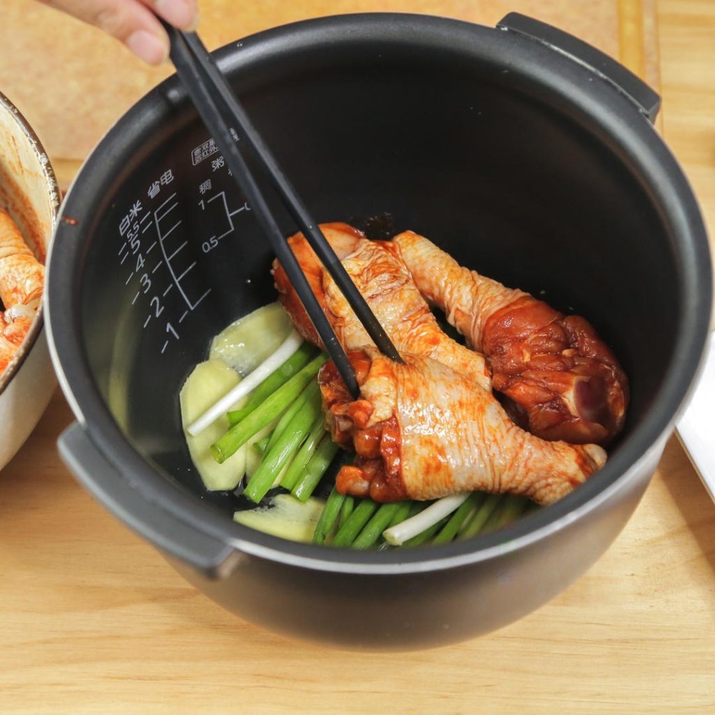 Place the marinated drumsticks on top of the aromatics. Pour any remaining marinade from the bowl over the chicken. Add an additional 5 spoons of water.