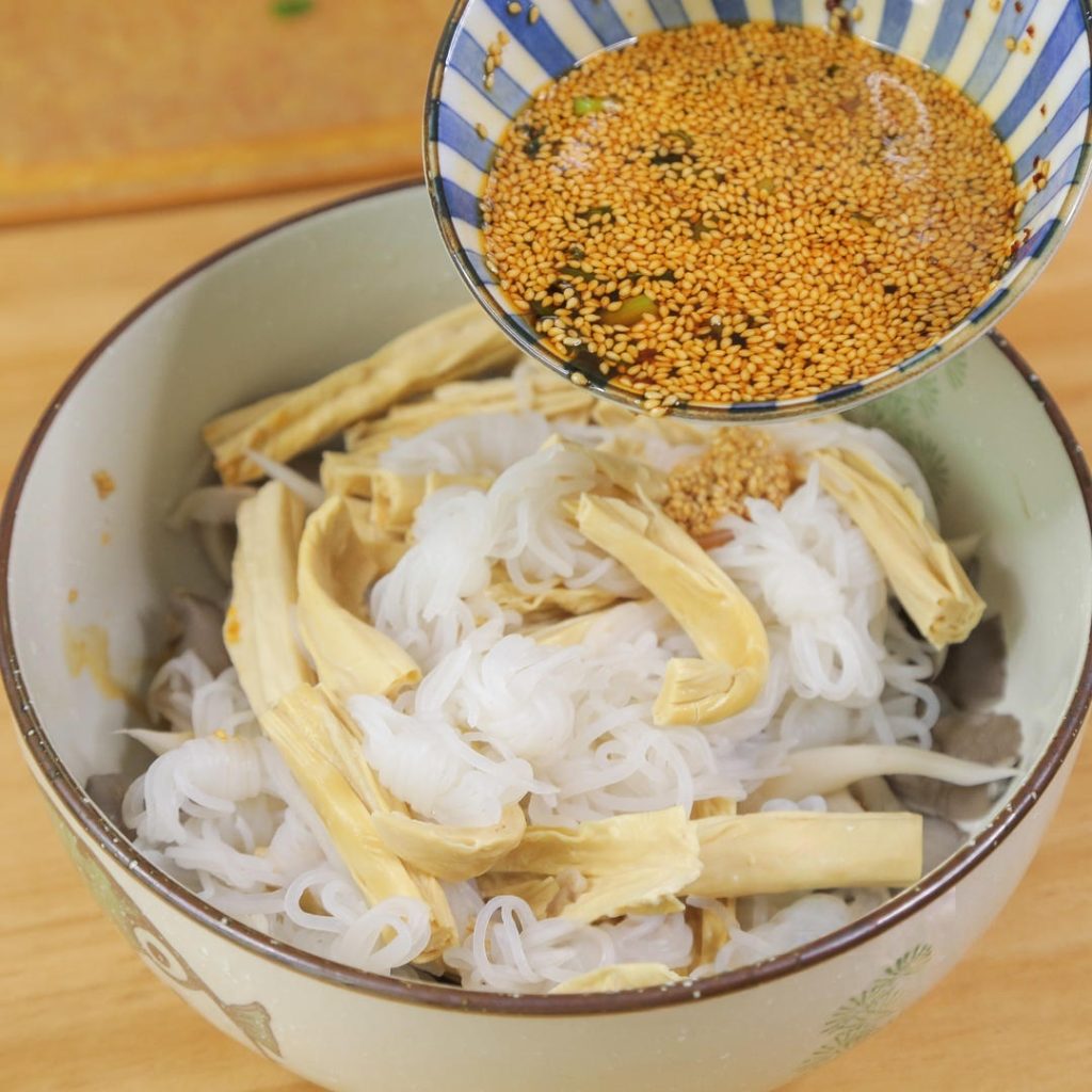 Pour the dressing over the drained mushrooms, konjac, and yuba. Add the lemon slices and fresh chili peppers. Toss everything together until well coated.