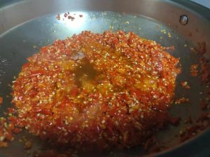 Add the minced chilies first and stir-fry until the oil turns red. Then add the ginger and garlic, stirring constantly until fragrant.