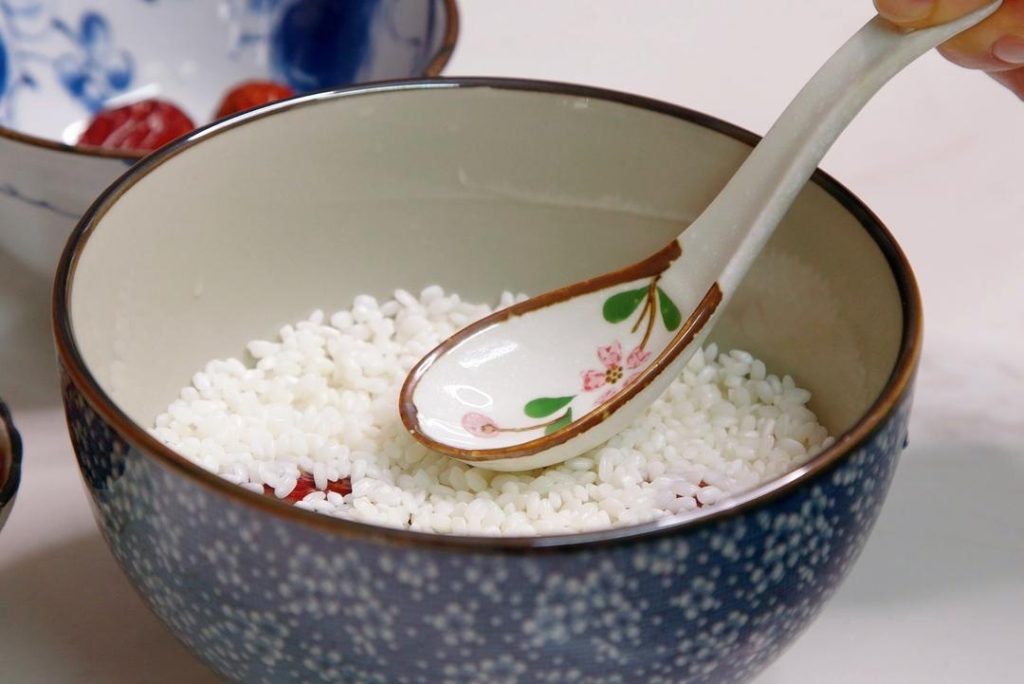 First Rice Layer Gently spread half of the drained sticky rice over the dried fruit.