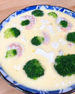 Gently arrange the blanched shrimp and broccoli on top of the egg mixture.