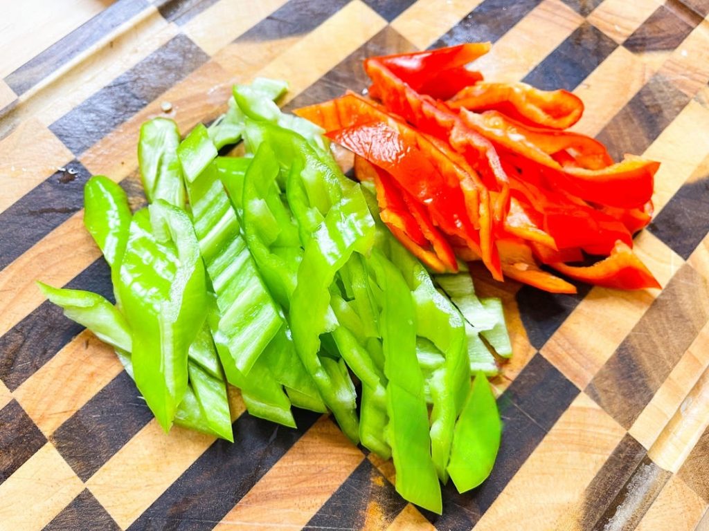 Remove the seeds and white pith from the peppers (unless you want it very spicy) and slice them into strips. Smash the 6 garlic cloves with the flat side of your knife to release their oils.