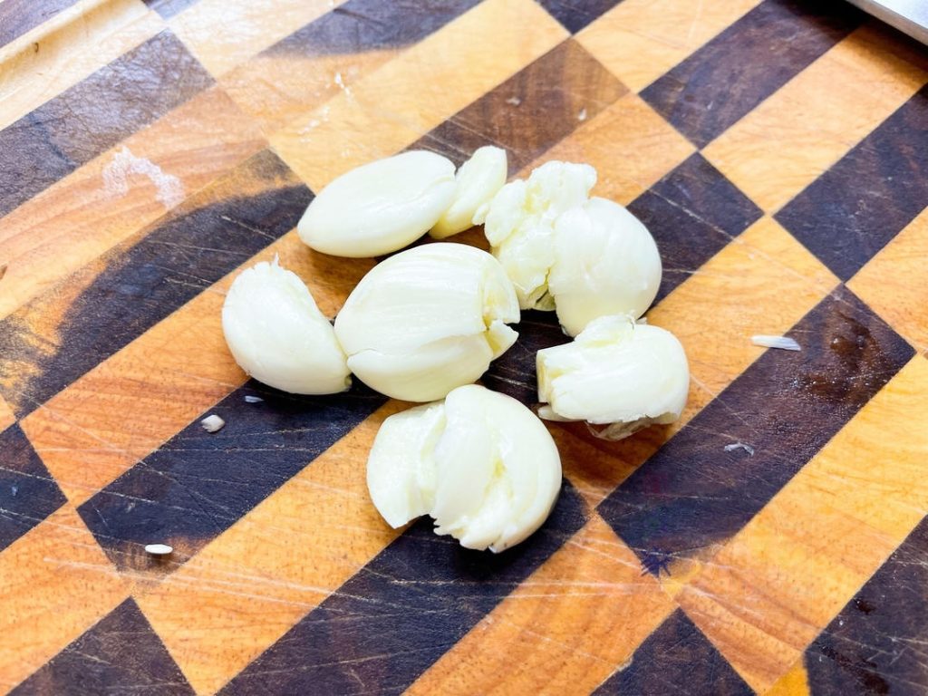 Smash the 6 garlic cloves with the flat side of your knife to release their oils.