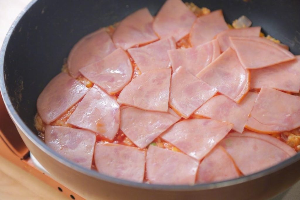 Spread the ketchup (tomato sauce) over the top of the rice, just like you are saucing a pizza. Arrange the ham slices evenly on top.