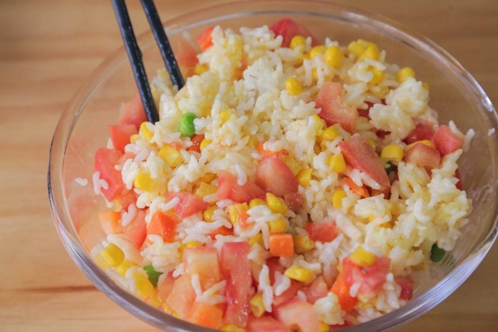 In a large mixing bowl, combine the cold leftover rice, the raw cracked egg, the diced tomato, and the mixed vegetables. Stir this mixture thoroughly.