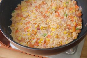 Add the rice mixture to the pan. Stir-fry constantly over medium heat. You want to cook until the egg coating on the rice solidifies and the grains start to separate.