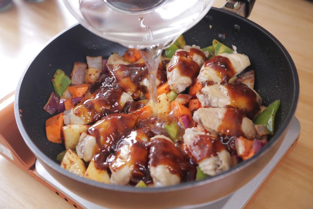 Add a small bowl (about 1/2 cup) of water, pouring it gently over the wings to help distribute the sauce.