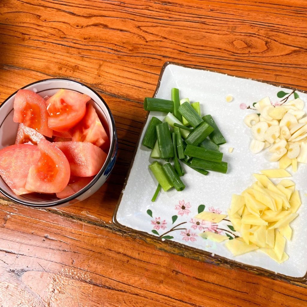 Prep Aromatics: Cut the tomato into small chunks. Slice the ginger and scallion whites into small pieces.