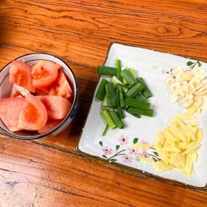 Prep Aromatics: Cut the tomato into small chunks. Slice the ginger and scallion whites into small pieces.