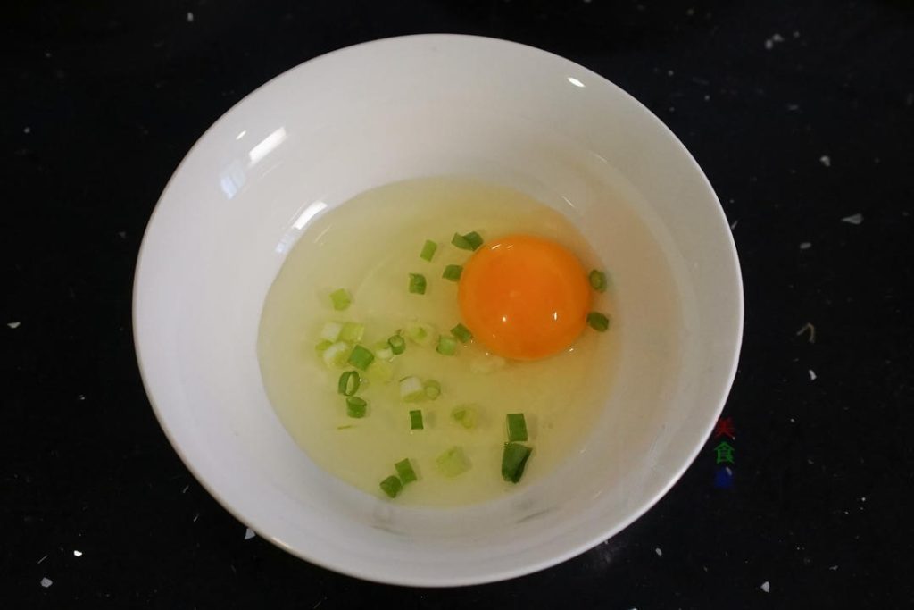 First, wash your scallions and chop them into small rings. Crack the eggs into a small bowl, add the chopped scallions and a pinch of salt, and whisk well until combined.