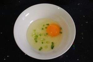 First, wash your scallions and chop them into small rings. Crack the eggs into a small bowl, add the chopped scallions and a pinch of salt, and whisk well until combined.