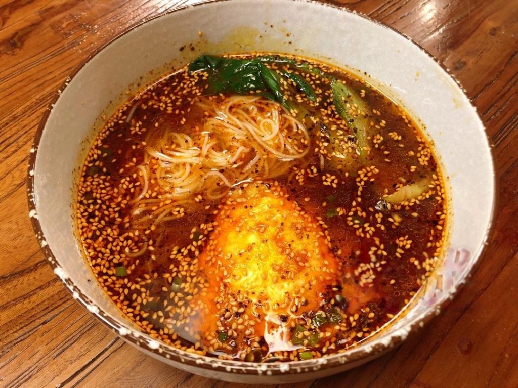 Transfer the cooked noodles and greens into the sour soup.