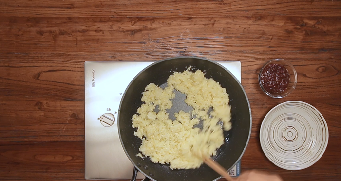 Place your cold cooked rice into a large mixing bowl. Crack the two eggs directly over the rice. Using chopsticks or a spatula, mix vigorously until every grain of rice is coated in the yellow egg mixture.