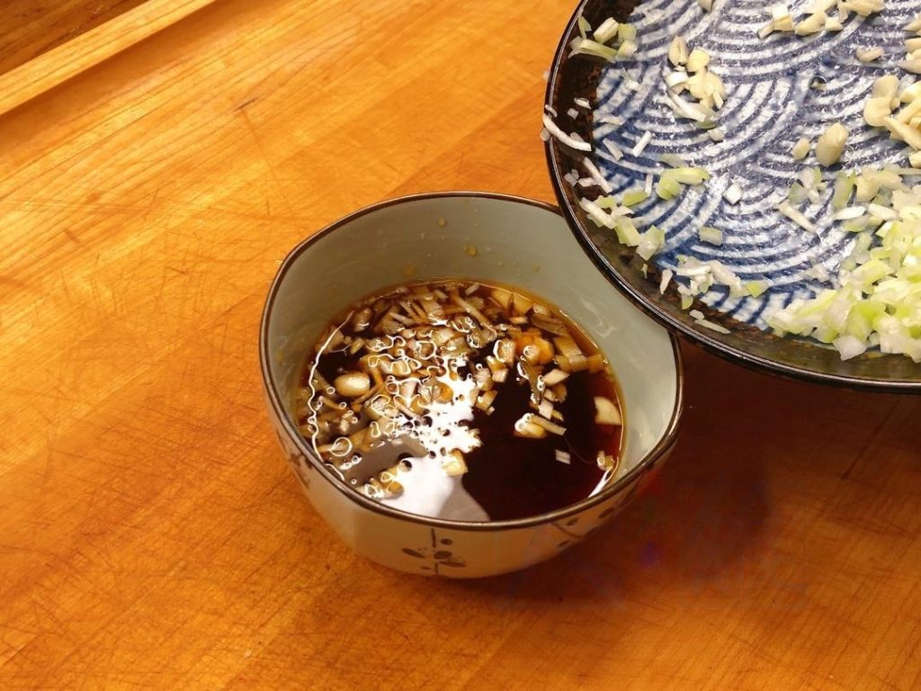 Add half of your minced garlic and scallions directly into this sauce bowl. This allows the aromatics to infuse the liquid. Save the rest for the stir-fry.