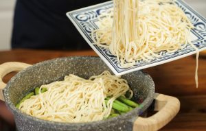 Layer the Noodles: Spread the fresh noodles evenly over the top of the green beans and pork. Try not to let the noodles touch the sides of the hot wok too much to prevent burning. Cover the lid immediately.