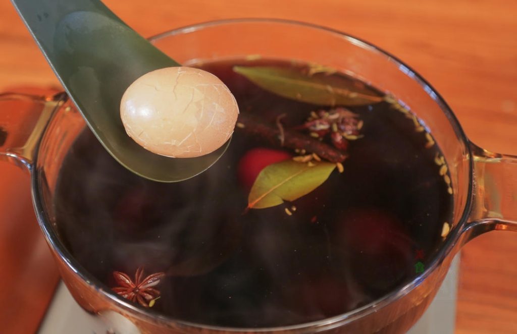 Simmer Gently lower the cracked eggs into the boiling brine. Reduce the heat to low. Cover and simmer for 20 minutes.
