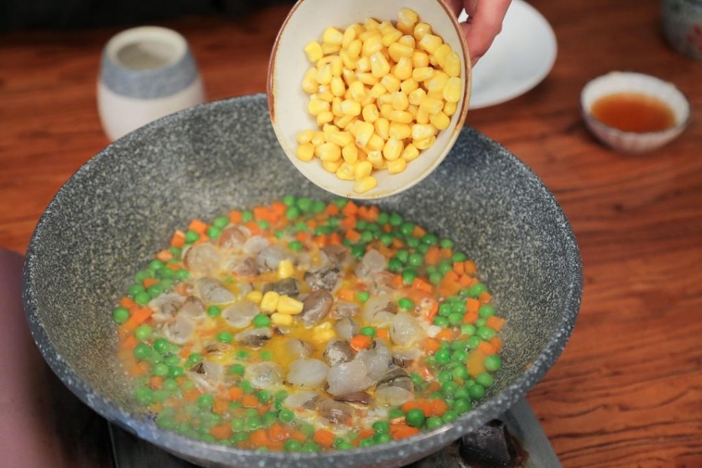 Cook the Shrimp and Corn Once the seasoned liquid is simmering, add the cut shrimp and the sweet corn kernels. Turn the heat to medium. Simmer for about 3 minutes.