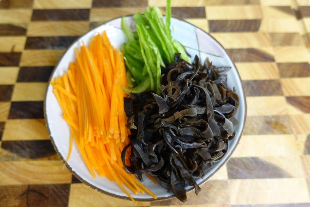 Slice the carrots, bell peppers, and rehydrated wood ear mushrooms into fine shreds.