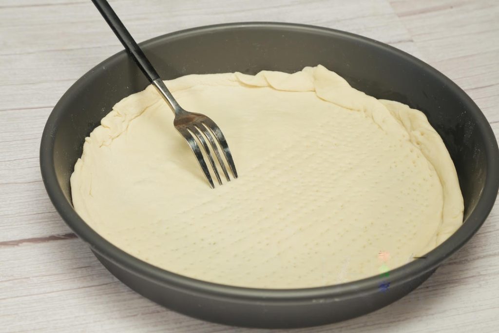 Shape the Dough: Once the dough has risen, punch it down to release air. Roll it out into a round circle to fit your pizza pan (about 9-10 inches). Brush the pan with a little oil, place the dough inside, and use a fork to poke holes all over the surface (this is called docking).