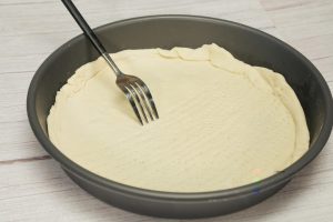 Shape the Dough: Once the dough has risen, punch it down to release air. Roll it out into a round circle to fit your pizza pan (about 9-10 inches). Brush the pan with a little oil, place the dough inside, and use a fork to poke holes all over the surface (this is called docking).