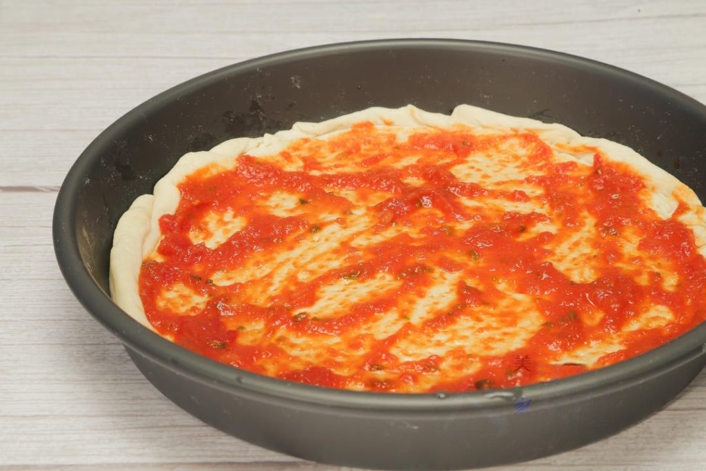 Assemble: Spread a layer of pizza sauce over the dough.
