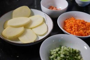 Wash and peel your potato. Cut it into thick slices (this helps it steam faster). Finely dice the carrot, cucumber, and ham.