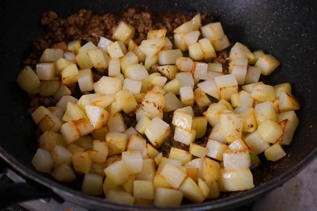 Add the pre-fried potatoes back into the wok.