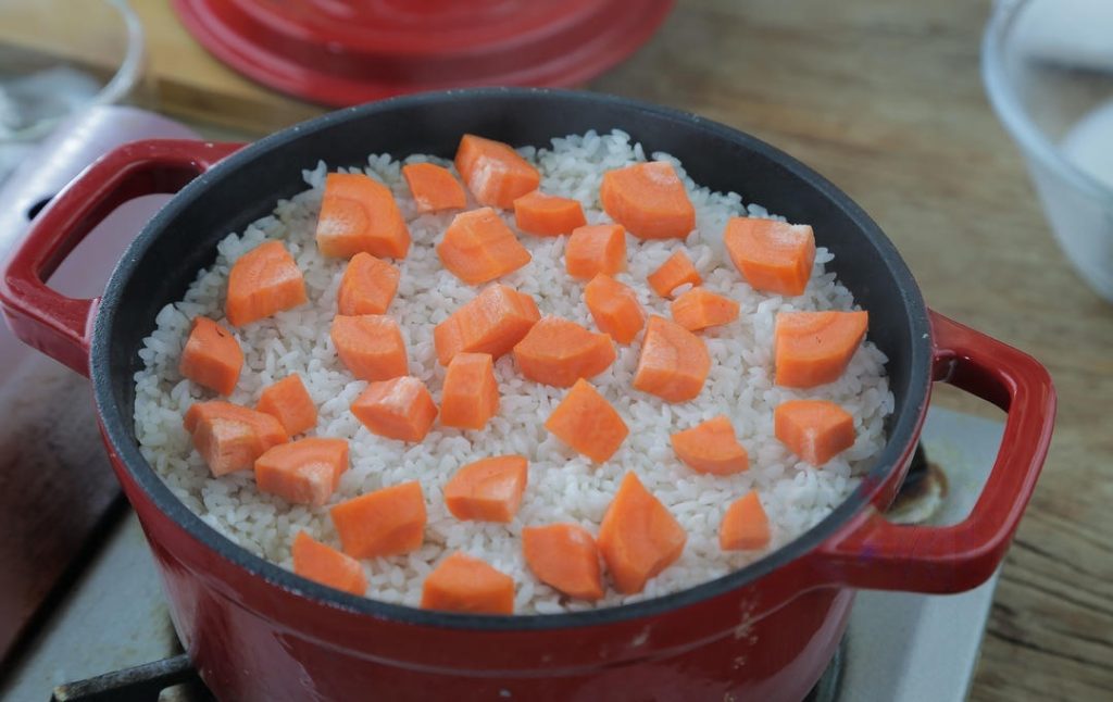 Final Steaming: Pour in the reserved mushroom soaking water. The liquid should just barely cover the surface of the rice. Sprinkle carrot dics on top.
